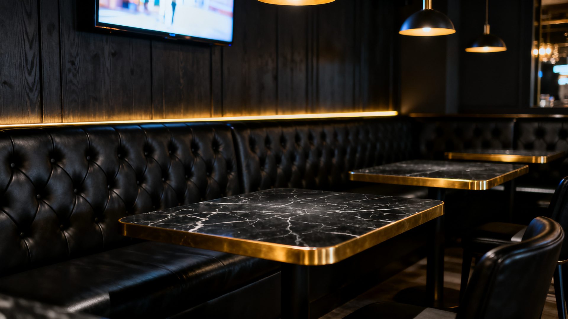 Tufted leather booths and glowing screens inside The SandLot